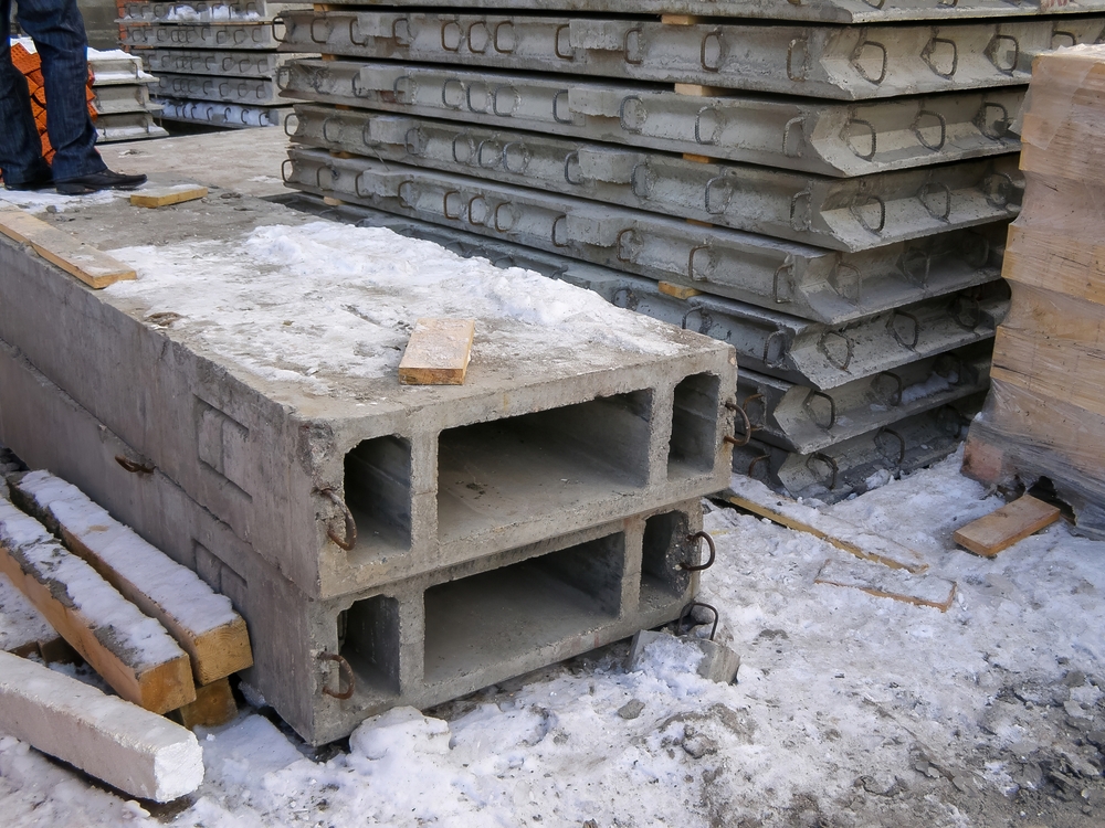 Concrete,slabs,and,beams,are,stacked,outdoors,during,winter,construction,