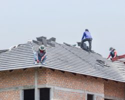 Workers,installing,concrete,tiles,on,the,roof,while,roofing,house